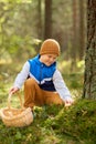 Happy boy with basket picking mushrooms in forest Royalty Free Stock Photo