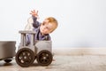 Happy boy blond in a blue sweater sits on a wooden floor. One year old baby playing with wooden toys. He want to take cat. Toys