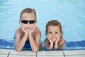 Happy boy with blond hair and little girl smiling sitting in swimming pool Royalty Free Stock Photo