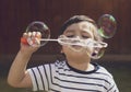 Happy boy blowing soap bubbles in the garden,Cute 4 years old kid blowing bubble wand with a funny face,Cute kid playing in the ga Royalty Free Stock Photo