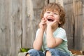 Happy boy. Cheerful childrens smile. Childrens happiness. A child sits in the garden near a wooden fence.