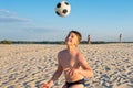 Happy boy cheerfully plays football on the beach, on a sunny day. Outdoor sports games. Active healthy lifestyle concept