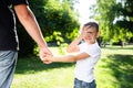 Happy boy child is smiling, hold fathers hand and covers his facr with his hand. Portrait of young boy in nature, park, outdoor. Royalty Free Stock Photo