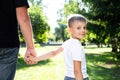 Happy boy child is smiling and hold fathers hand. Portrait of young boy in nature, park, outdoor. Summer recreation with family. Royalty Free Stock Photo