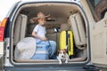 Happy boy in a cowboy hat and puppy jack russell terrier travel by car. A child and a funny little dog are sitting in Royalty Free Stock Photo