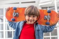 Happy boy with denim jacket and his skateboard on his back Royalty Free Stock Photo