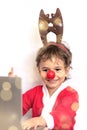 happy boy dressed as Rudolph reindeer waves his hand while looking at laptop screen, on white background with bokeh