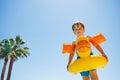 Happy boy in duckling buoy and arm floaties stand over blue sky Royalty Free Stock Photo