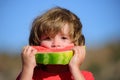 Happy boy eating watermelon. Cute boy eating healthy food melon in nature background. Fresh organic watermelons. Royalty Free Stock Photo