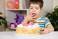 A happy boy eats a birthday cake, eats with his hands and licks his fingers. Royalty Free Stock Photo