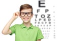 Happy boy in eyeglasses over eye chart