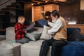 Happy boy with funny modern grandpa fighting with pillows having fun together sitting on comfortable couch at home. Royalty Free Stock Photo