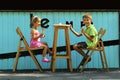 Happy boy and girl, brother and sister, eating ice cream in the open air outdoor sidewalk city cafe