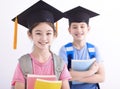 Happy boy and  girl in graduation cap holding books Royalty Free Stock Photo