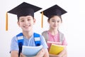 Happy boy and girl in graduation cap holding books Royalty Free Stock Photo