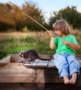 Happy boy go fishing on the river with pet, one children and kitten of the fisherman with a fishing rod on the shore of the lake Royalty Free Stock Photo