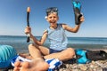 Boy has water polo ball and scuba gear on the beach. Looking at camera. Concept of travel, tourism, family Royalty Free Stock Photo