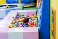 Happy boy having fun in ball pit in kids amusement park and indoor play center. Child playing with colorful balls in playground Royalty Free Stock Photo