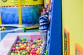 Happy boy having fun in ball pit in kids amusement park and indoor play center. Child playing with colorful balls in playground Royalty Free Stock Photo