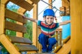 Happy boy having fun and playing at adventure park, holding ropes and climbing wooden stairs