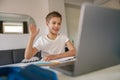 Small happy boy having online video lesson at laptop sitting in his room and waving hi Royalty Free Stock Photo