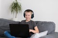 Happy boy in headphones playing online video game on laptop computer at home. Child sitting and use pc Royalty Free Stock Photo