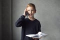 A happy boy is holding a book in his hands and talking on the phone Royalty Free Stock Photo