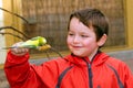 Happy boy holding and feeding parakeet