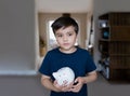 Happy boy holding piggy bank with smiling face. Portrait of a cheerful child showing money saving box.School kid Learning Royalty Free Stock Photo