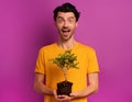 Happy boy holds a small tree ready to be planted over a light color. concept of forestation, ecology and conservation