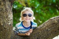 Happy boy on holiday resting on a tree