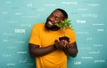 Happy boy hugs a small tree ready to be planted over a light blue color. Concept of forestation, ecology and