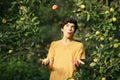 Happy boy juggling apples smile wink on apple tree green garden background