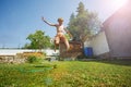 Happy boy jump over garden lawn sprinkler - summer fun Royalty Free Stock Photo
