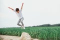 Happy boy jumping from stone  against green grass. Soft focus. Summer activities Royalty Free Stock Photo