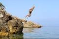 Happy boy jumps from rock into sea Royalty Free Stock Photo