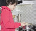 Happy Boy is in kitchen on a stove cooking soup Royalty Free Stock Photo