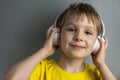 Happy boy listening to music on headphones isolated on gray background Royalty Free Stock Photo