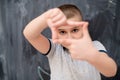 Happy boy making hand frame gesture in front of chalkboard Royalty Free Stock Photo