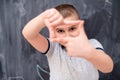 Happy boy making hand frame gesture in front of chalkboard Royalty Free Stock Photo