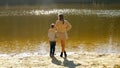 Happy boy with mother standing on riverbank at sunset rays. Family outdoors, happy parenting and childhood, autumn landscape, kids Royalty Free Stock Photo