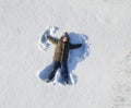 Happy boy play on snow and making snow angel figure with hands and legs