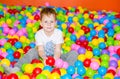 Happy boy playing in ball pit on birthday party in kids amusement park and indoor play center. Child playing with Royalty Free Stock Photo