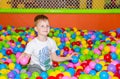 Happy boy playing in ball pit on birthday party in kids amusement park and indoor play center. Child playing with Royalty Free Stock Photo