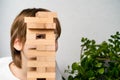 a happy boy is playing a board game, building a tower of wooden cubes, hiding behind a tower of cubes, a logical jenga Royalty Free Stock Photo