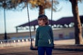 Happy blond boy playing in the park on chain swing Royalty Free Stock Photo