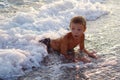 A happy boy is playing in the waves on the beach. Royalty Free Stock Photo