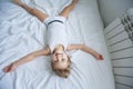 Happy kids playing in white bedroom. Little boy and girl, brother and sister play on the bed wearing pajamas. Family at Royalty Free Stock Photo