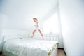 Happy kids playing in white bedroom. Little boy and girl, brother and sister play on the bed wearing pajamas. Family at Royalty Free Stock Photo