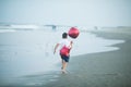 Happy boy plays with red balloons on the beach having great holidays time on summer. Lifestyle, vacation, happiness, joy concept Royalty Free Stock Photo